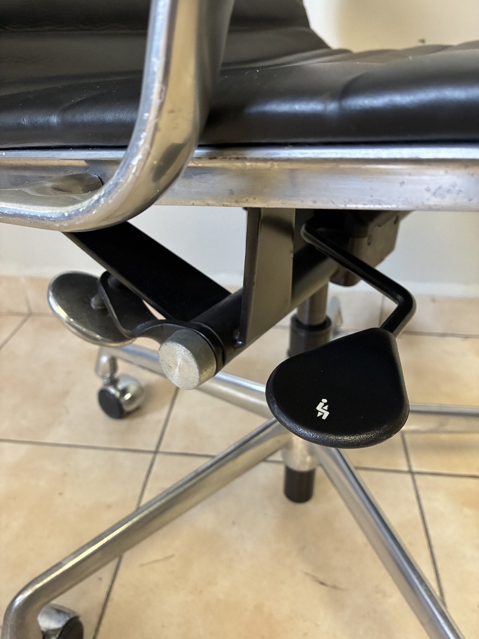 Silla ergonómica Eames Herman Miller preowned de piel negra, vista de cerca de los mecanismos de ajuste bajo el asiento.