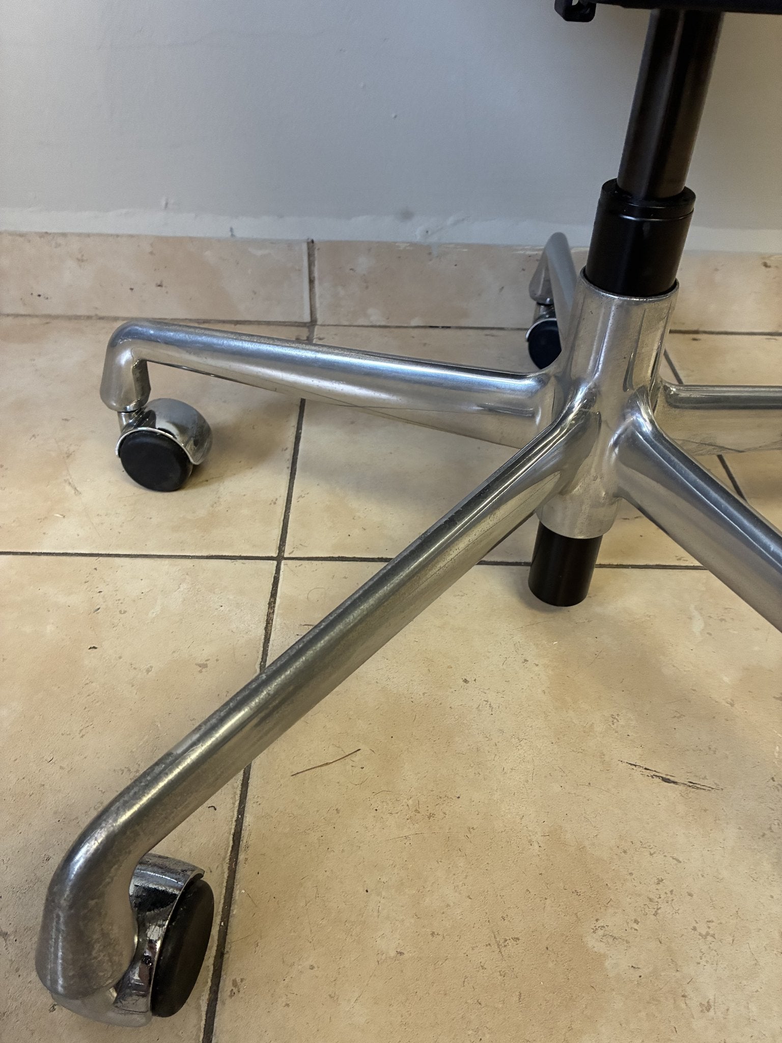 Base de silla ergonómica Herman Miller Eames de piel negra, con ruedas y estructura metálica brillante.