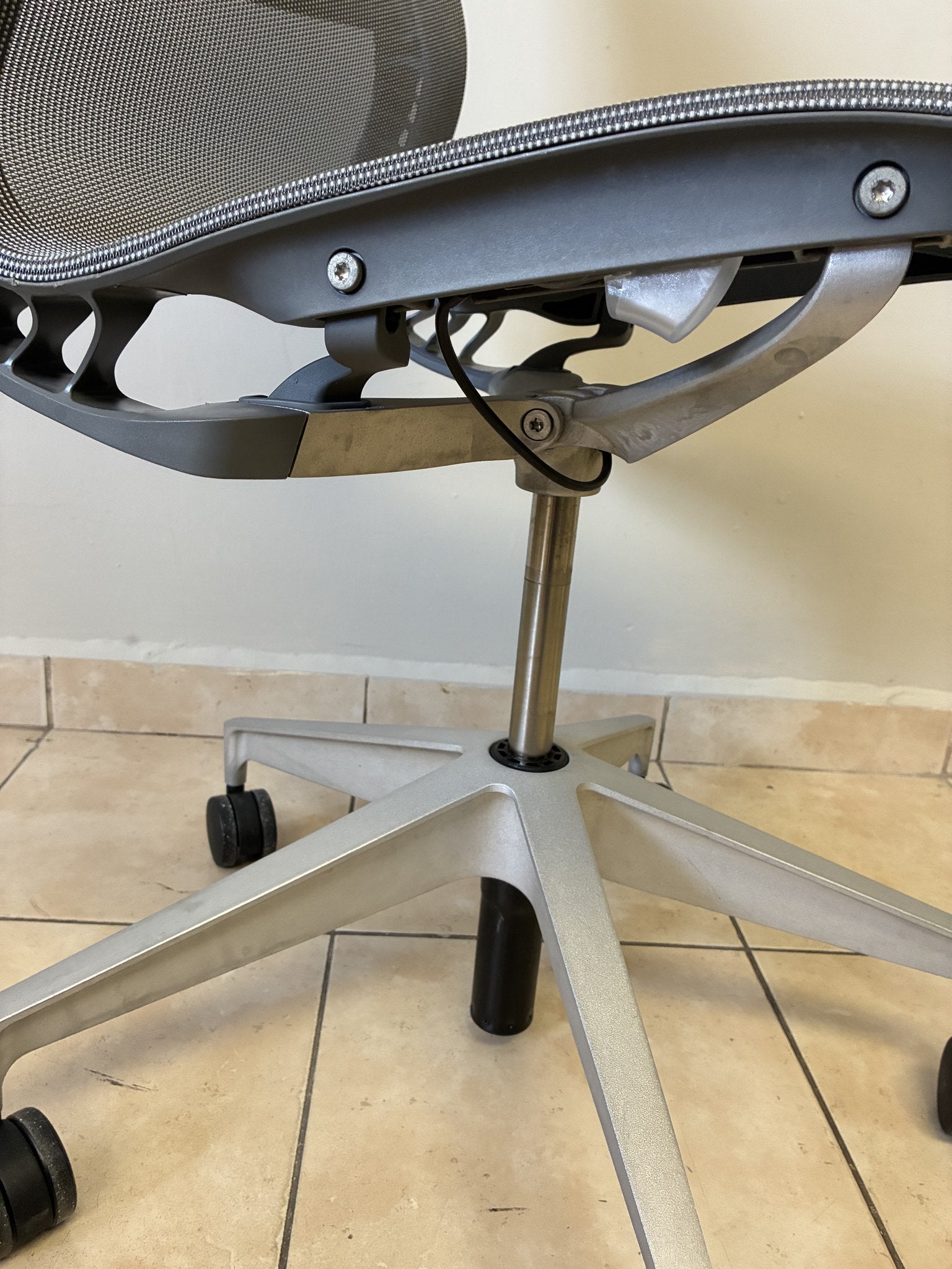 Silla de oficina Herman Miller Setu sin brazos, color gris claro, vista lateral de la base y mecanismo.