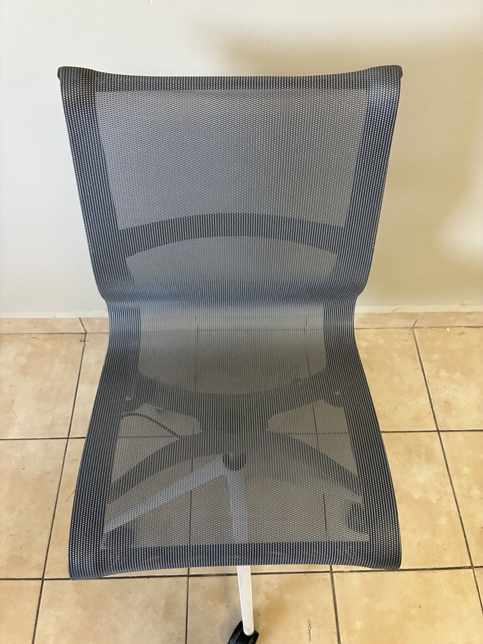 Silla de oficina Herman Miller Setu gris claro sin brazos, vista frontal de su respaldo y asiento de malla.