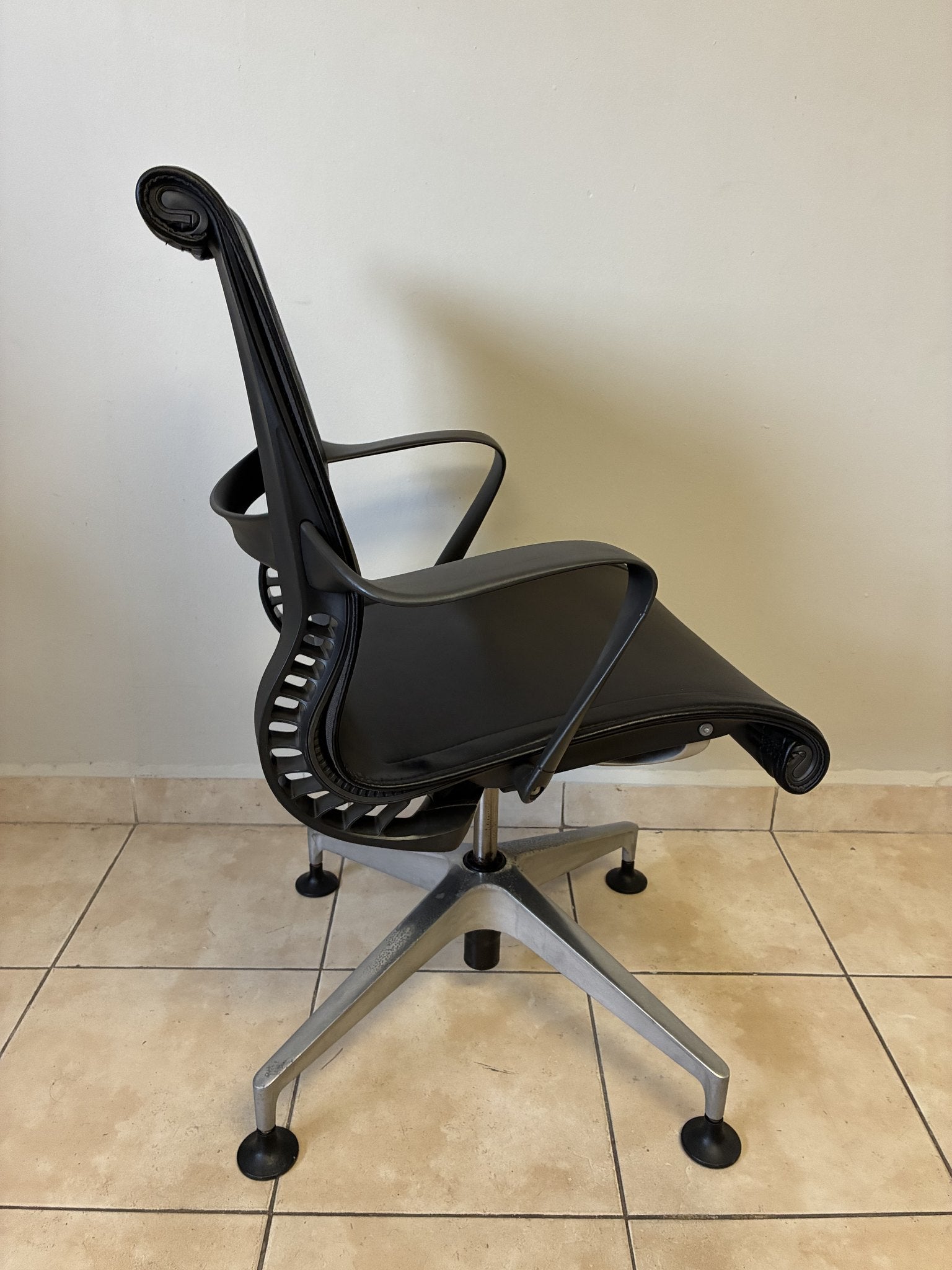Silla de oficina Herman Miller Setu fija preowned, de piel negra, vista lateral mostrando el respaldo y base.