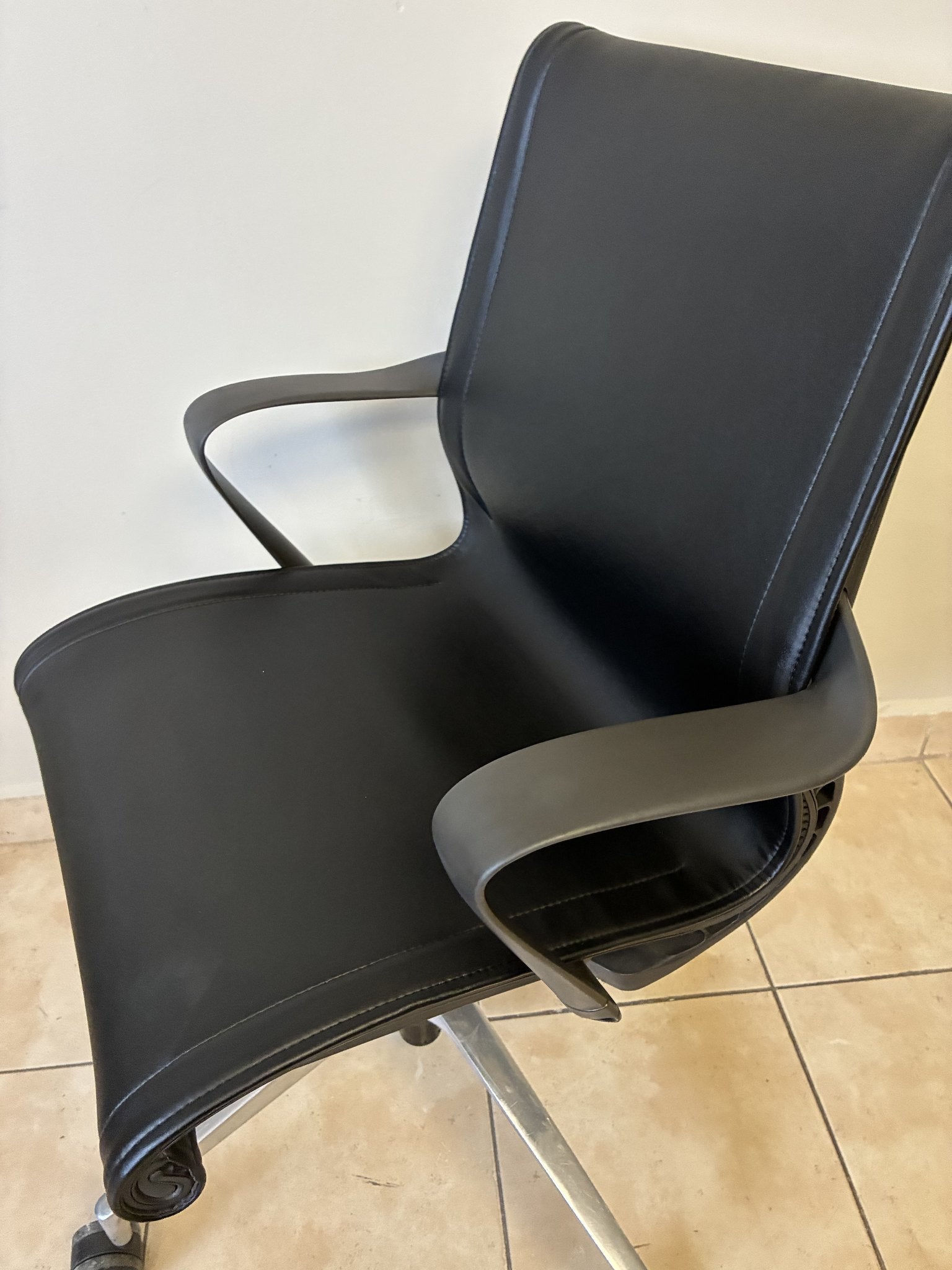 Silla de oficina Herman Miller Setu de piel negra, vista lateral de tres cuartos. Respaldo y asiento curvos.