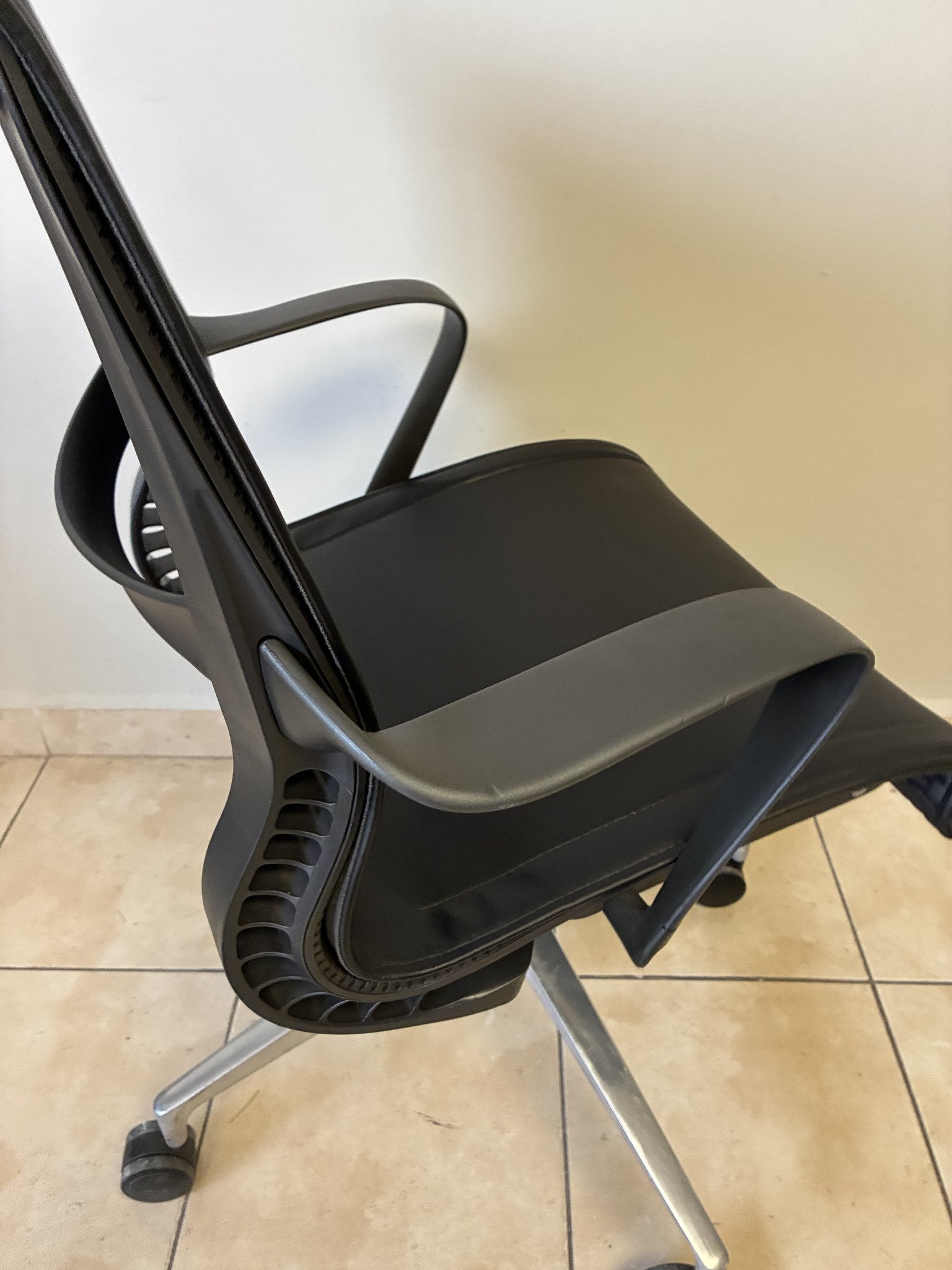 Silla de oficina Herman Miller Setu de piel negra, vista lateral. Base de aluminio y ruedas.