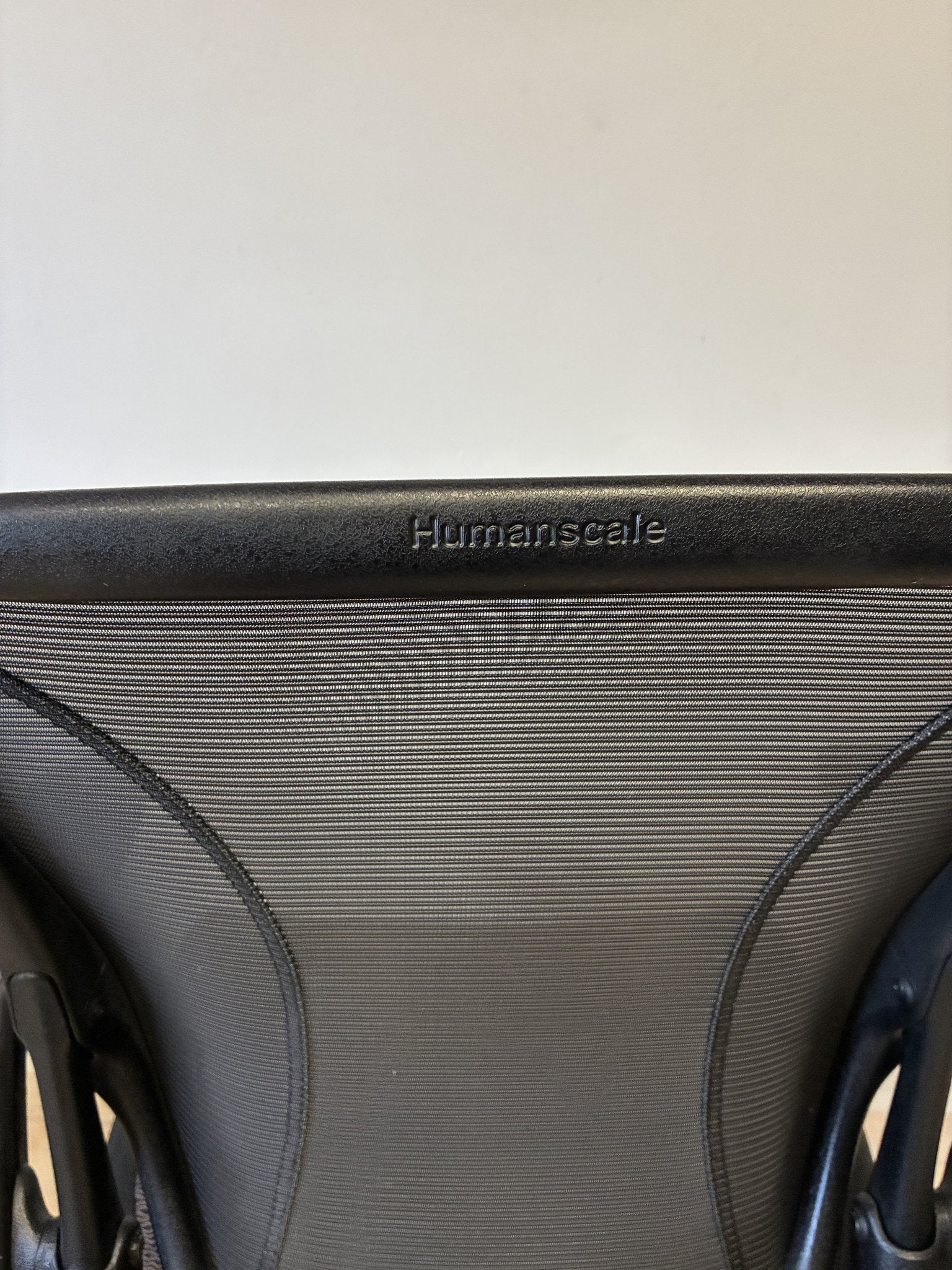Silla ergonómica Humanscale World Cafe, detalle del respaldo de malla negra con el logo de la marca.