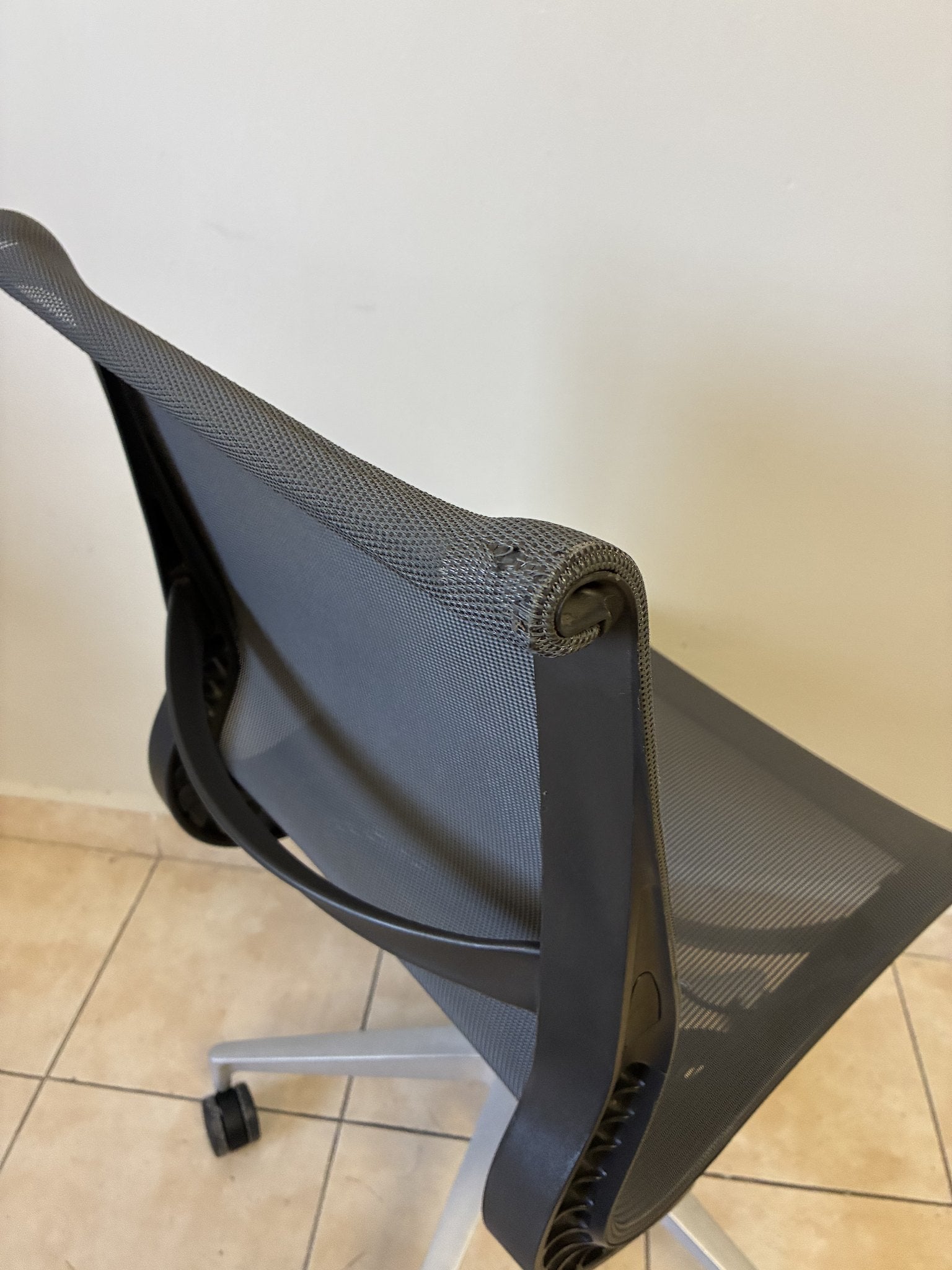 Silla de oficina Herman Miller Setu preowned, color gris oscuro sin brazos, vista trasera en ángulo.