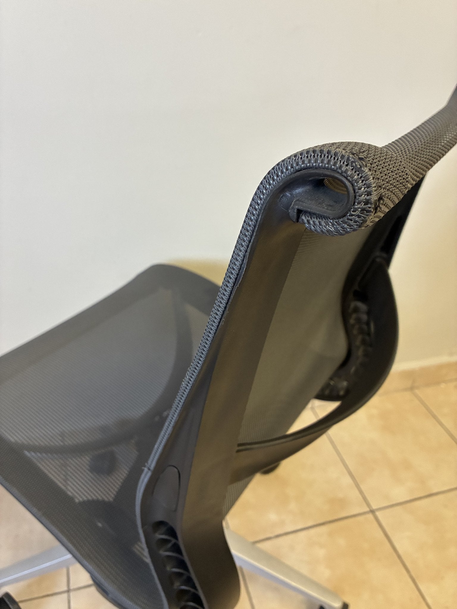 Silla de oficina Herman Miller Setu sin brazos, color gris oscuro, vista trasera de la curvatura del respaldo.