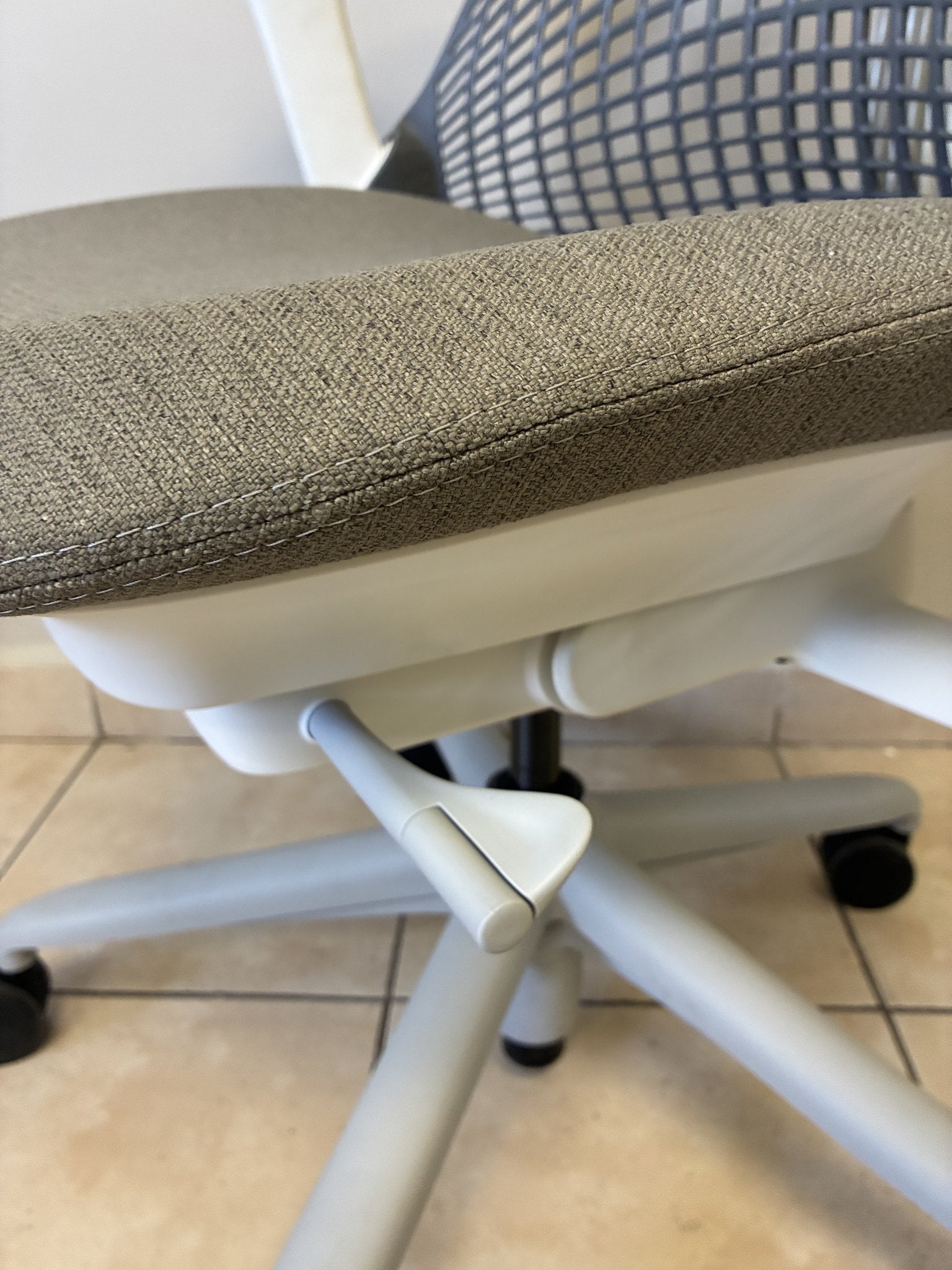 Silla de oficina Herman Miller Sayl pre-owned, asiento gris con base y estructura blanca, vista lateral.