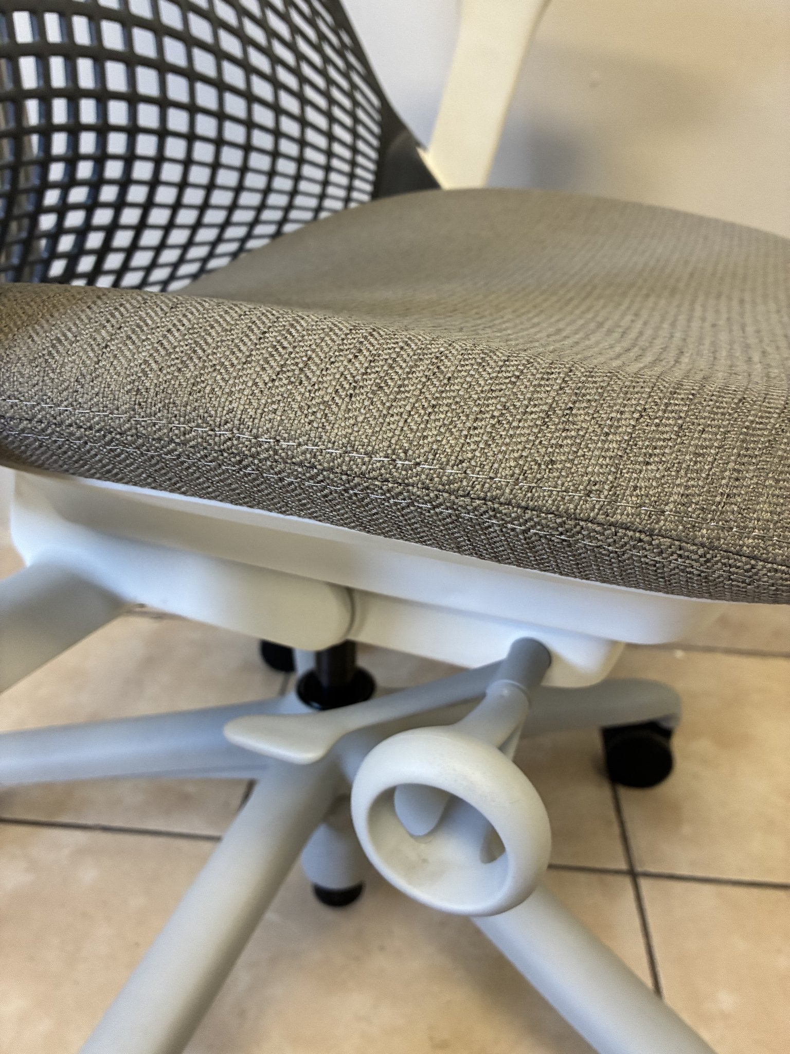 Silla de oficina Herman Miller Sayl preowned, asiento gris de tela texturizada y base blanca, vista lateral.