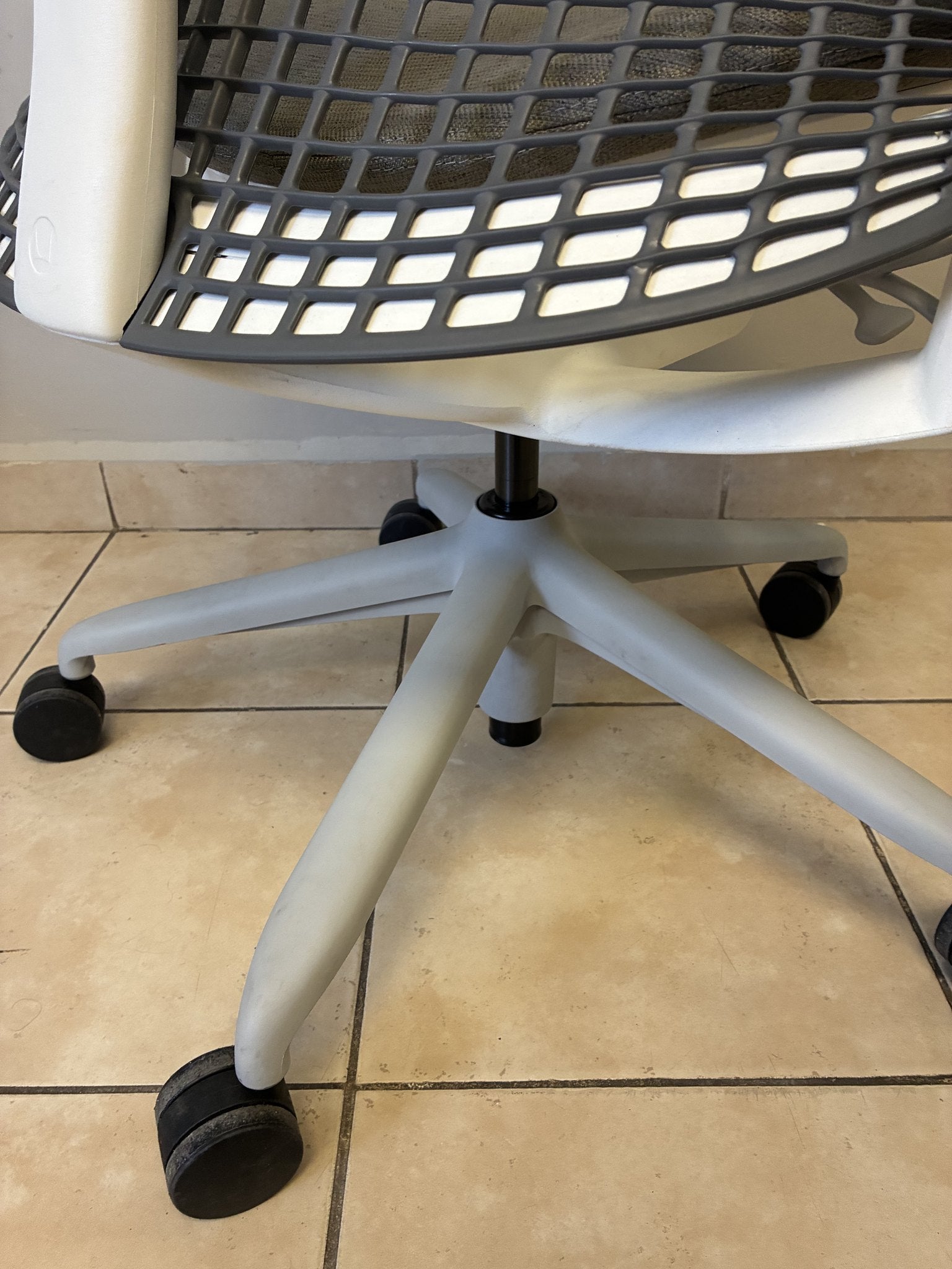 Silla de oficina Herman Miller Sayl preowned, base gris con ruedas negras, vista inferior y lateral.