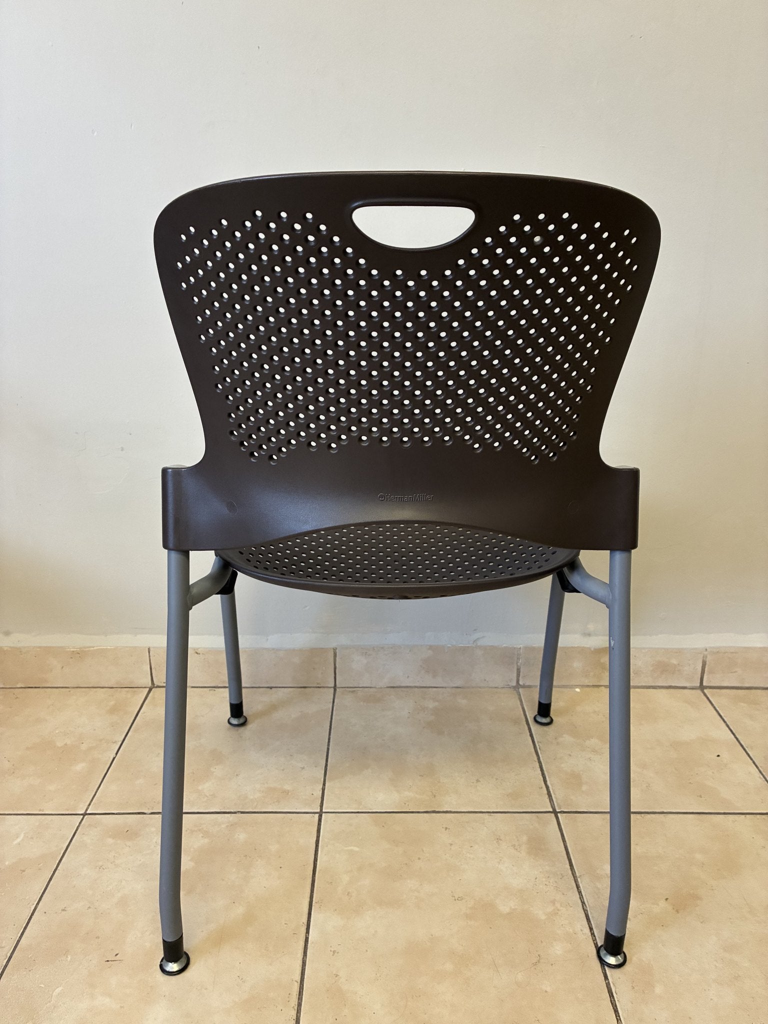 Silla ergonómica Caper de Herman Miller en color café, vista trasera. Diseño perforado y patas grises.