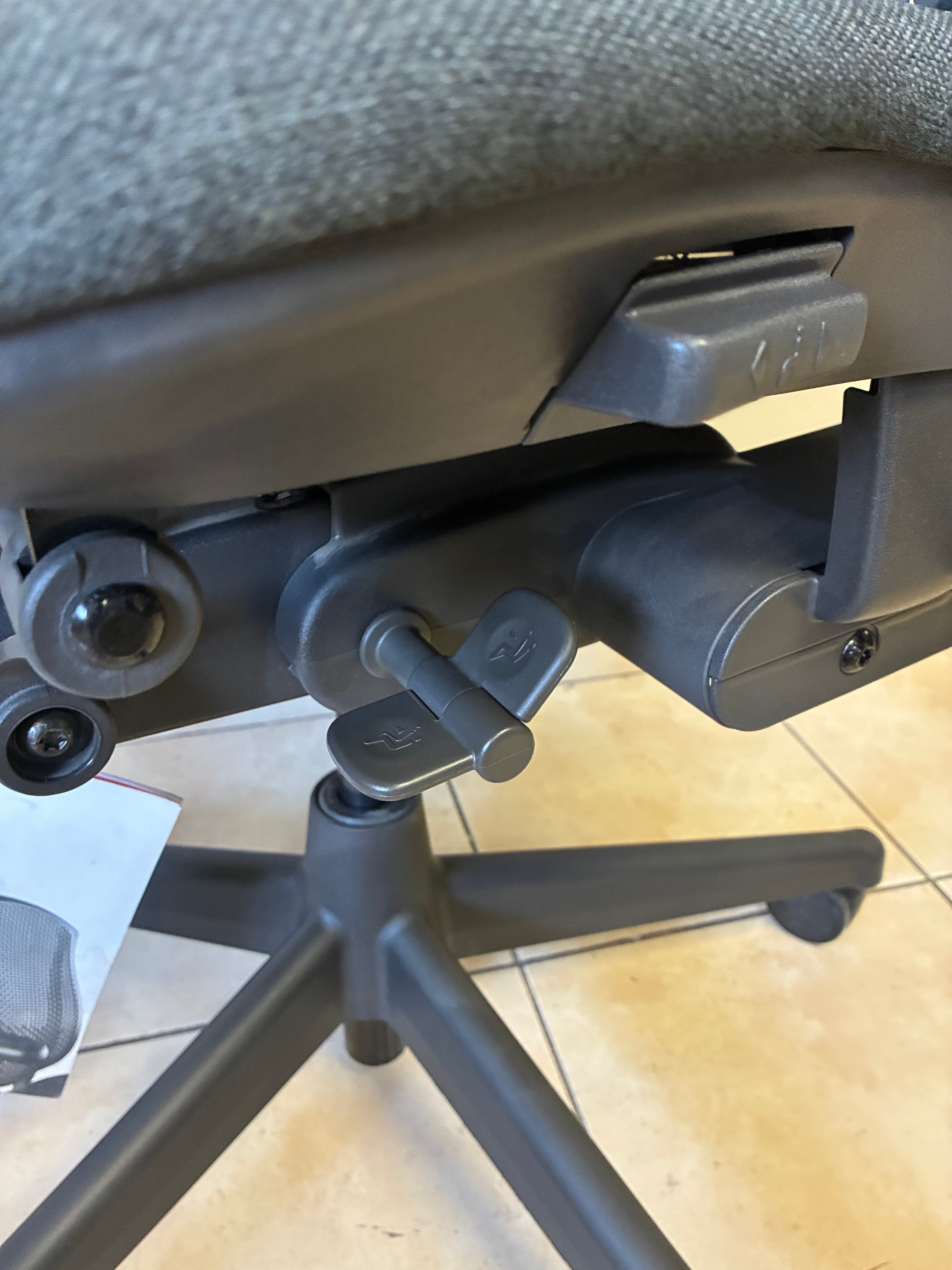 Silla de oficina Herman Miller Celle sin uso, vista inferior de los controles de ajuste en color gris oscuro.