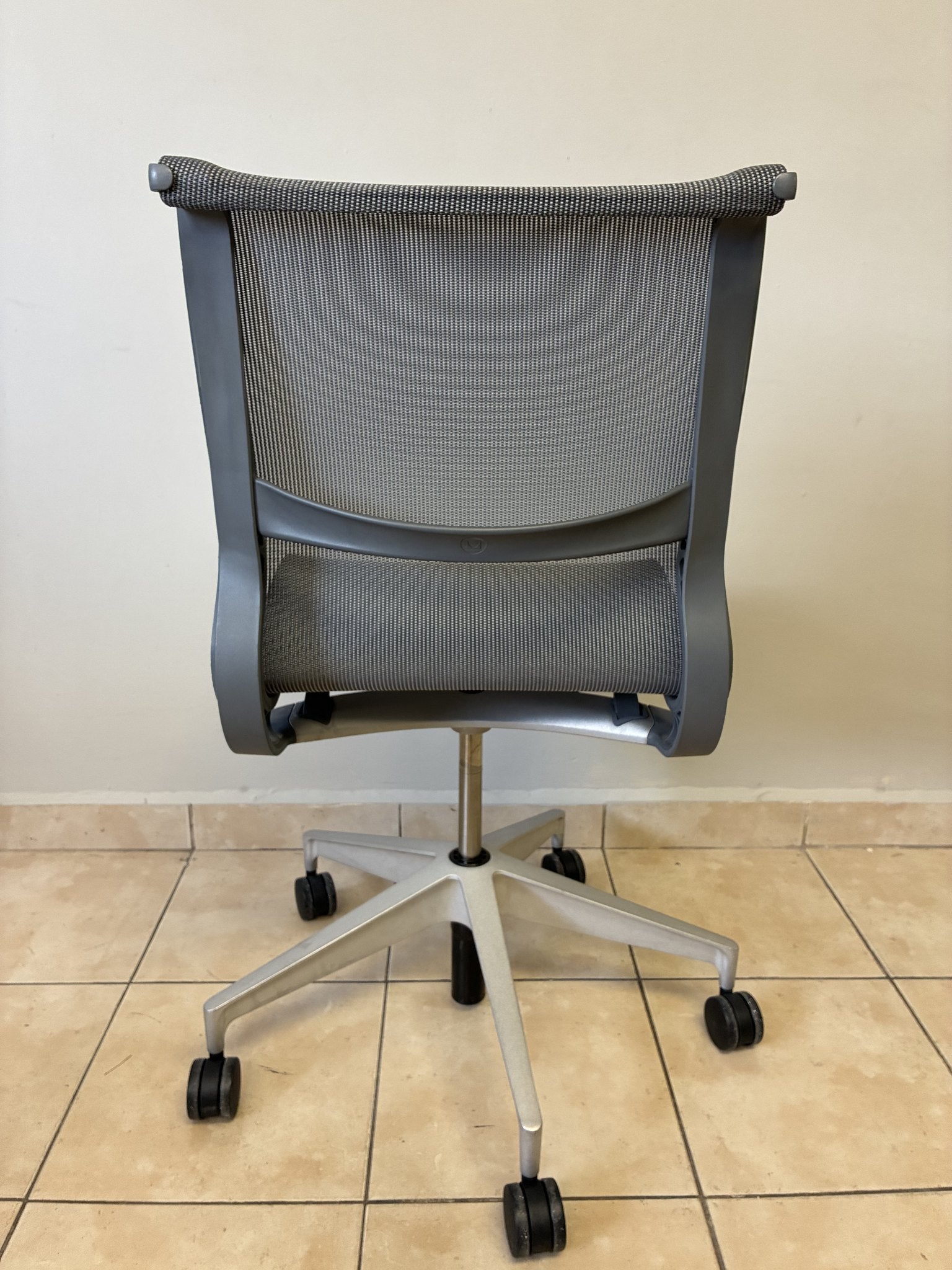 Silla de oficina Herman Miller Setu pre-owned, sin brazos, en color gris claro, vista trasera completa.