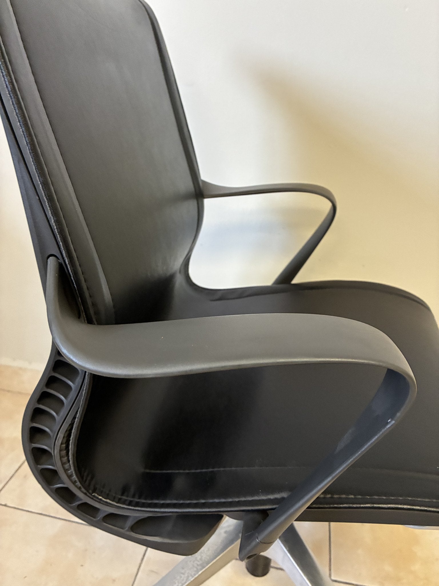 Silla de oficina Herman Miller Setu fija pre-owned, de piel negra, vista lateral que muestra los brazos.