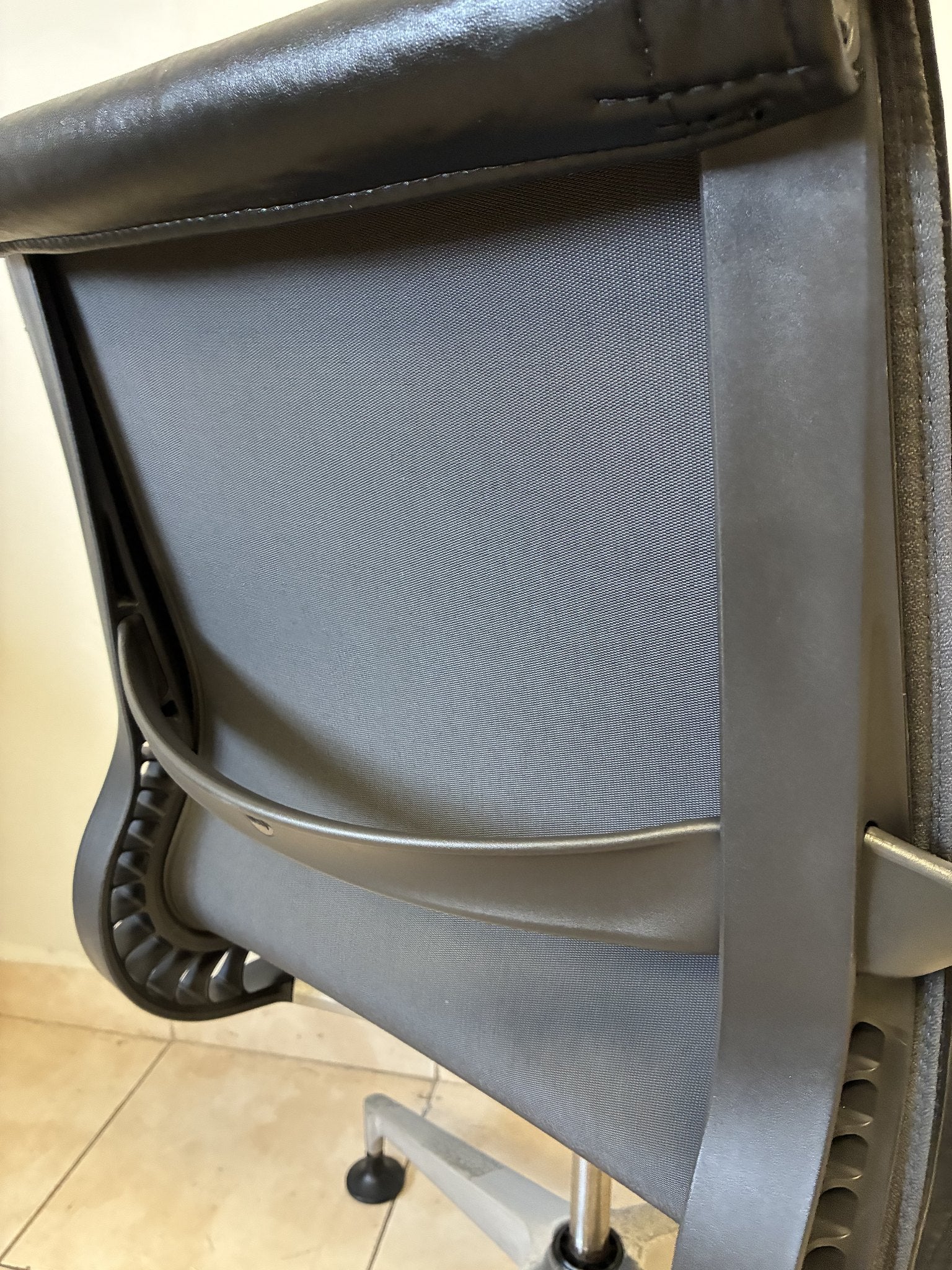 Silla de oficina Herman Miller Setu fija, respaldo de malla gris y borde de piel negra, vista trasera