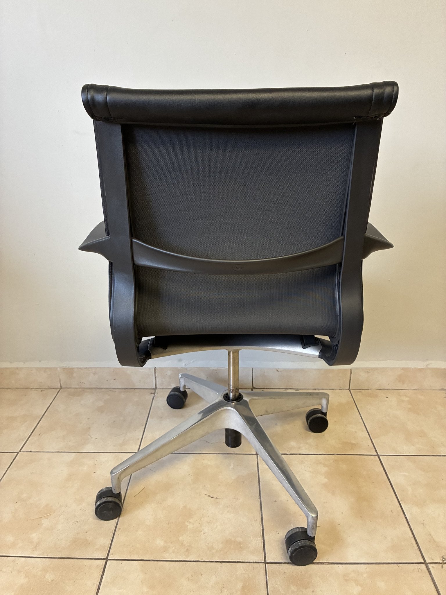 Silla de oficina Herman Miller Setu de piel negra, vista trasera completa, con base de aluminio y ruedas.