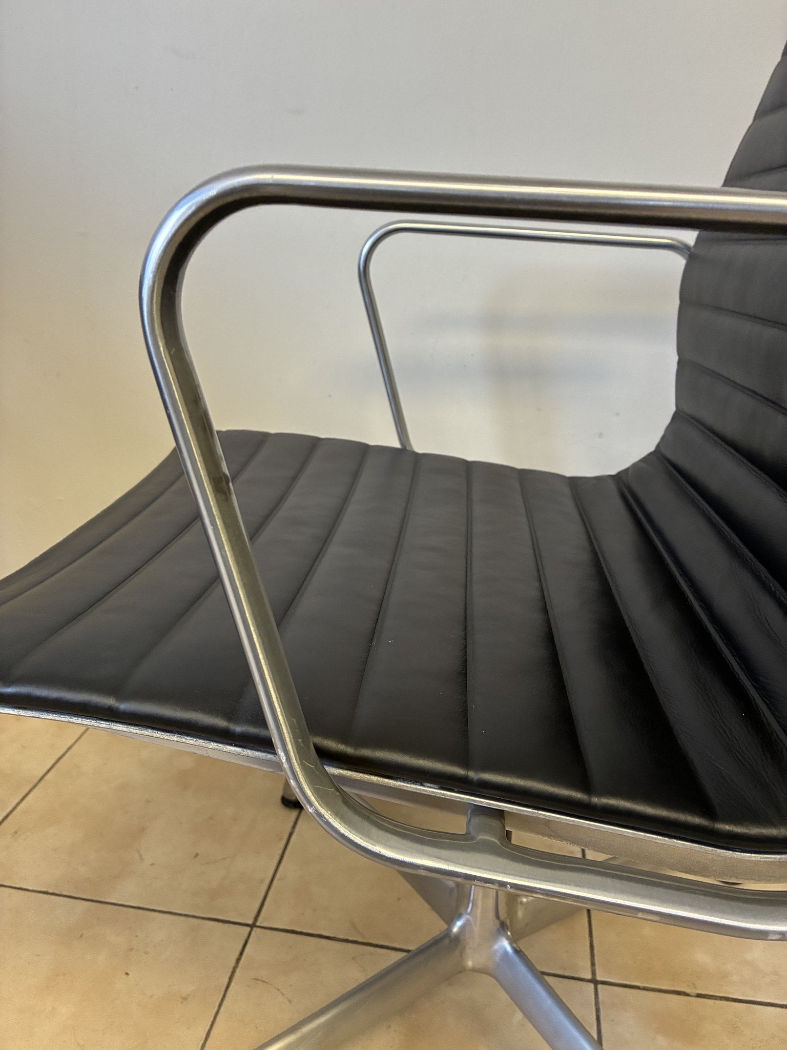 Silla Eames Herman Miller fija, piel negra, vista lateral. Diseño clásico y elegante, seminueva.