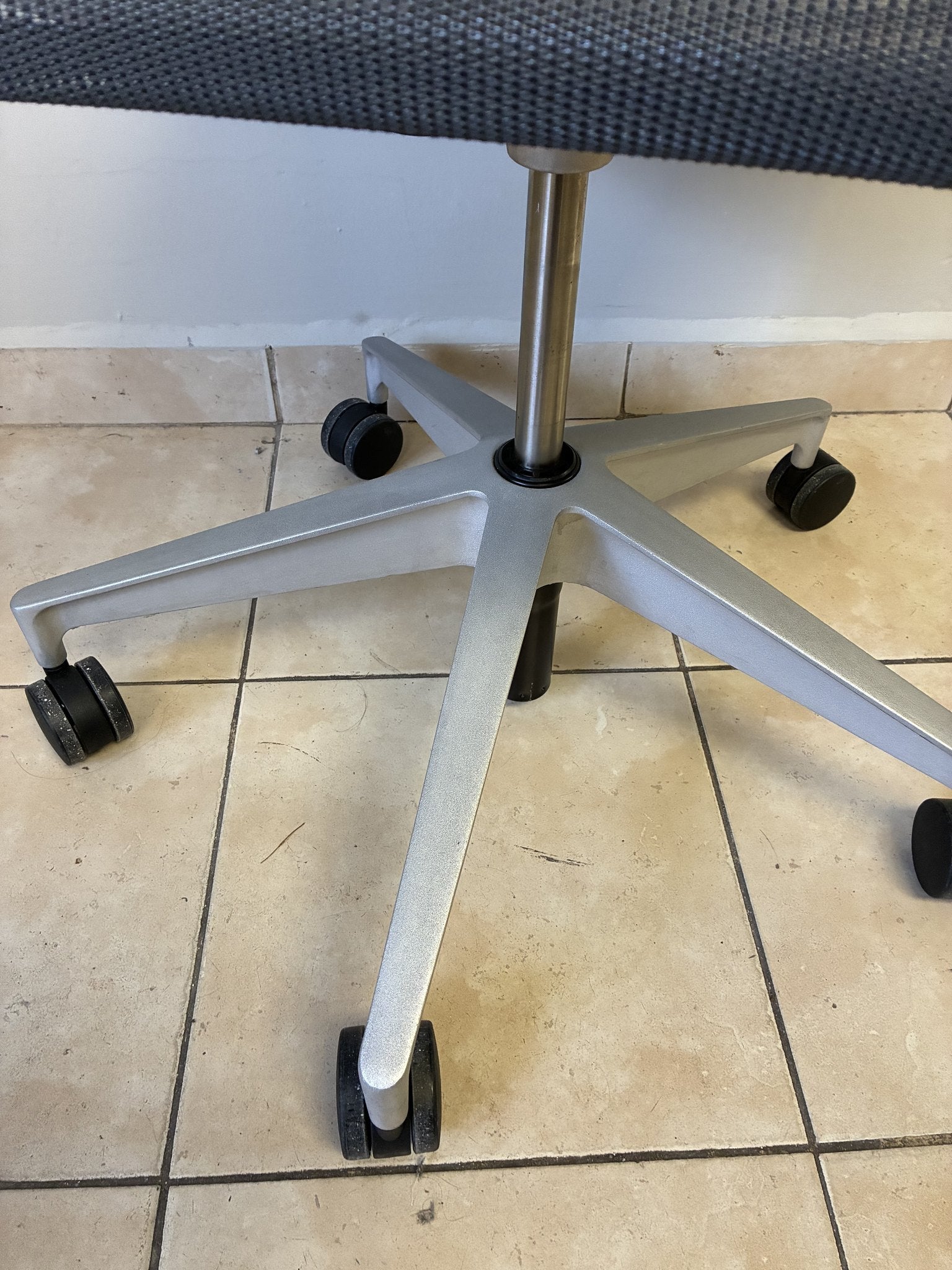 Silla de oficina Herman Miller Setu gris oscuro sin brazos, vista de la base de 5 ruedas de aluminio.
