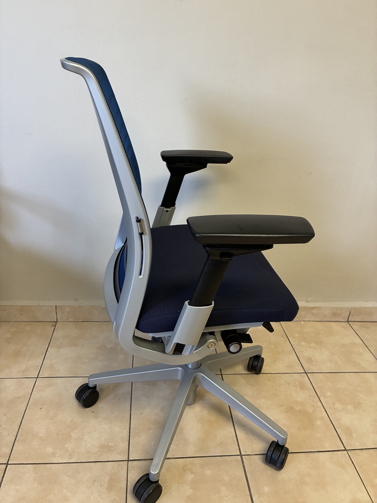 Silla ergonómica Steelcase Think V2 azul, vista lateral. Respaldo de malla y asiento tapizado en tela.