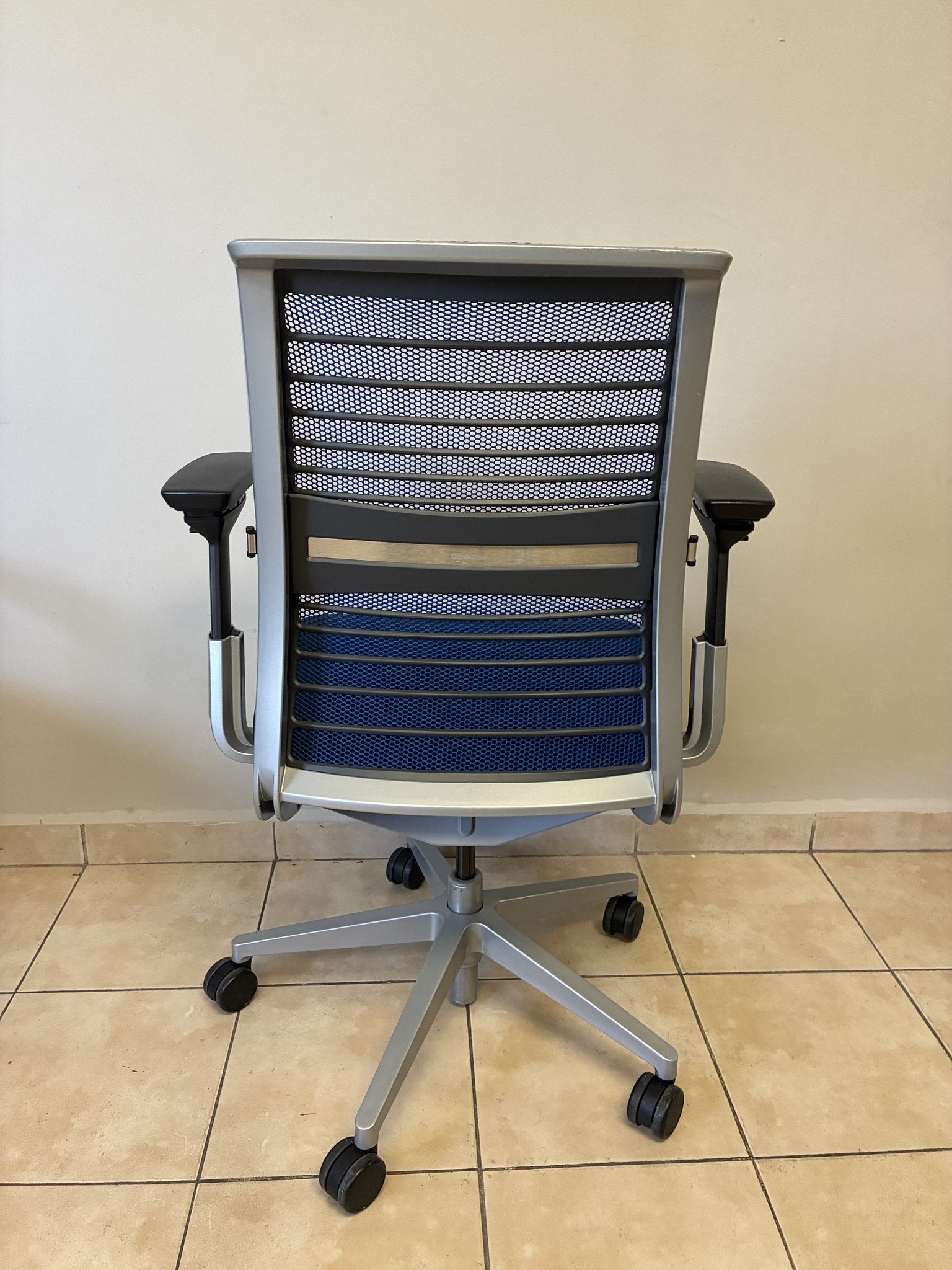 Silla ergonómica Steelcase Think V2 azul, preowned, vista trasera completa con base de ruedas.