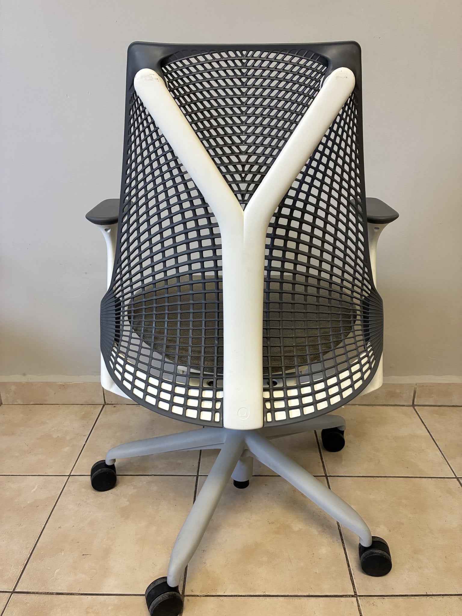 Silla de oficina Herman Miller Sayl preowned, respaldo de malla gris y soporte lumbar blanco, vista trasera.