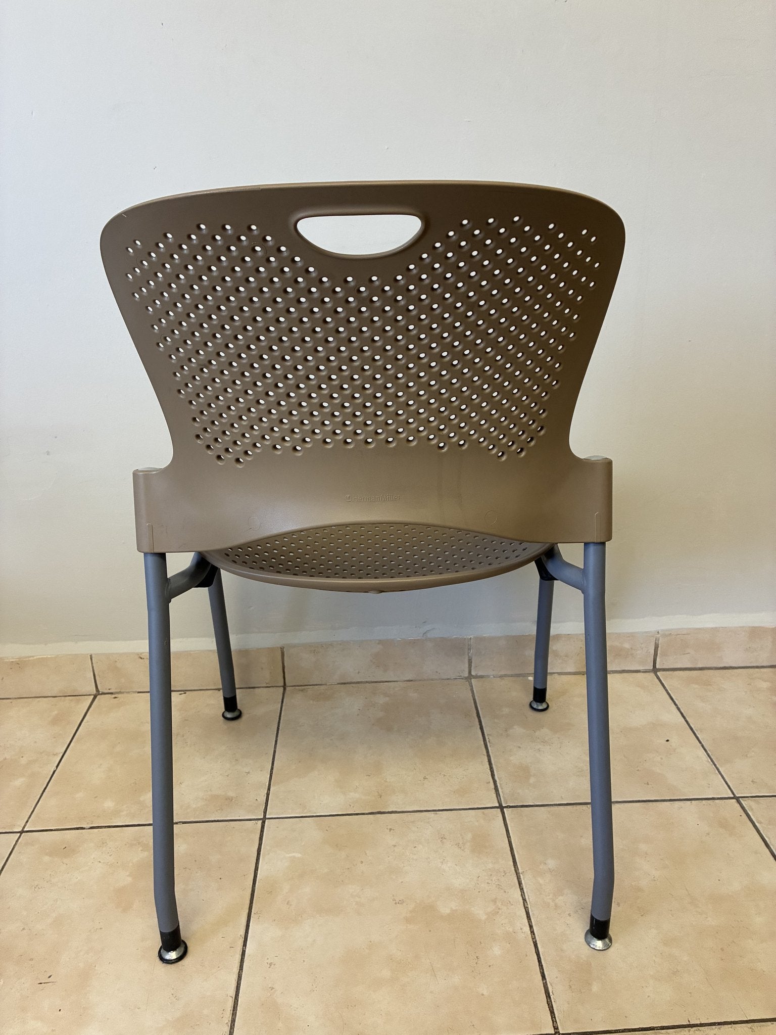 Silla Caper café claro Herman Miller, vista trasera. Respaldo perforado y patas de metal gris.